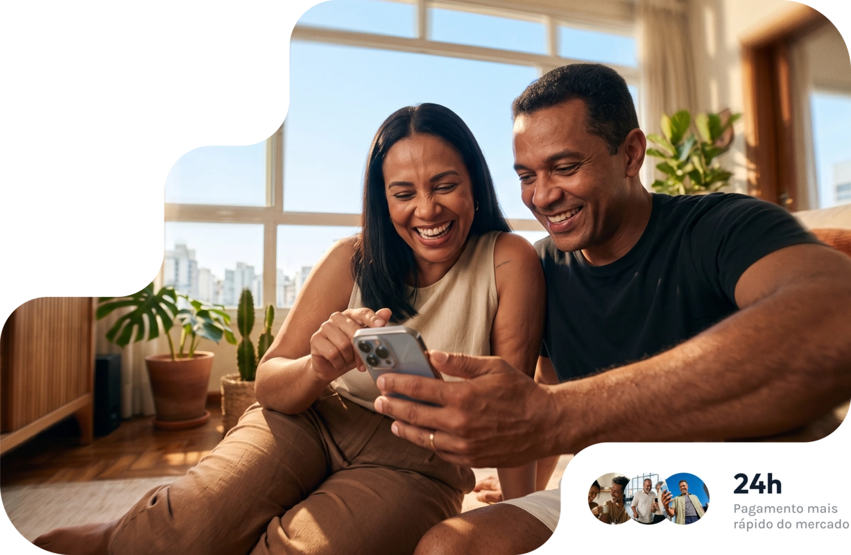 Casal sorrindo e olhando um celular, com plantas e luz natural